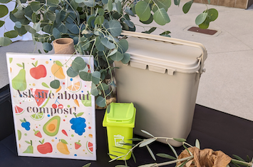 Table from the Sustainability Hub Open House featuring an "Ask Me About Compost Sign"